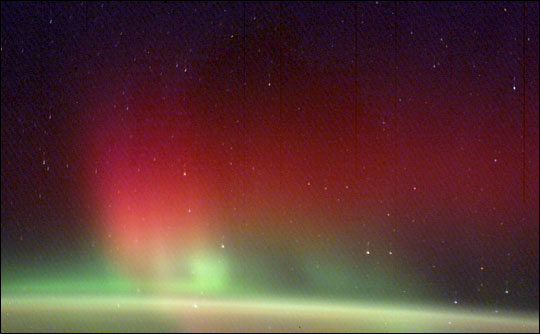 photograph of green aurora extending upward from the Earth’s airglow layer