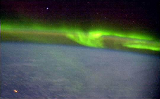 Photograph of swirls of bright green aurora above the airglow.