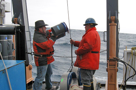 Scientists and crew sampling phytoplankton from the deck of the Delaware II in poor weather.
