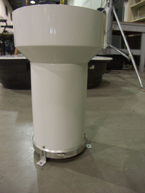 Cylindrical, white plastic exterior of a tipping bucket rain gauge.